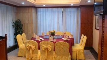 A conference room with a round table, yellow chairs with bows, and a red tablecloth.
