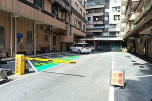 Une zone de stationnement avec des lignes peintes en jaune et en vert, un fourgon blanc et un immeuble à plusieurs étages doté de balcons.