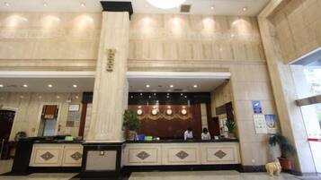 A hotel lobby with a reception desk, a large pillar, and a reception area.