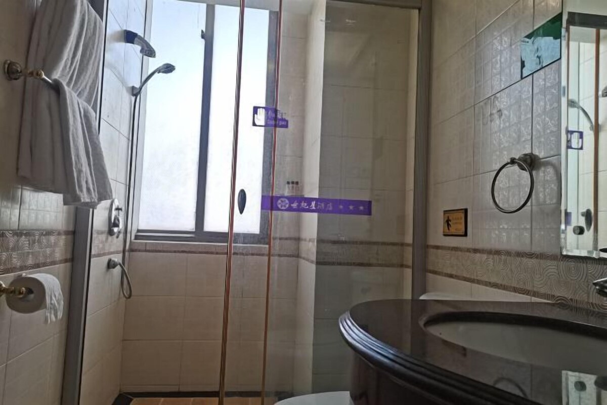 A bathroom with a shower, a toilet, and a sink. There is a window providing natural light.