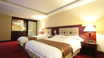 A hotel room with two beds, a red carpet, a wooden headboard, and a nightstand with a lamp.