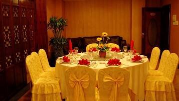 A round table with white tablecloth and yellow chairs, set for a meal with red napkins and a centerpiece of yellow flowers.
