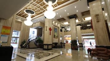 A spacious lobby with high ceilings, large columns, and a central staircase.