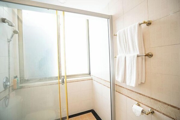 A glass-enclosed shower with a window, white tiled walls, and a towel rack with white towels. - Century Star Hotel (Foshan)