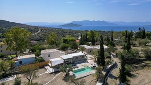 Une propriété située sur la côte, dotée d’une piscine, de bâtiments en pierre et offrant une vue sur la mer et les montagnes.