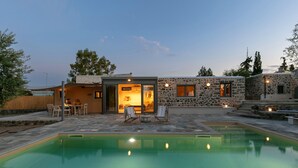 Une maison moderne dotée d’une piscine, de murs en pierre et d’un espace salon extérieur.