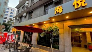 Façade d'un hôtel avec une enseigne indiquant « 海悦 » et un arbre en pot devant l'entrée.