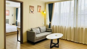 Une chambre d’hôtel avec un lit, un canapé, une petite table et une fenêtre avec des rideaux.