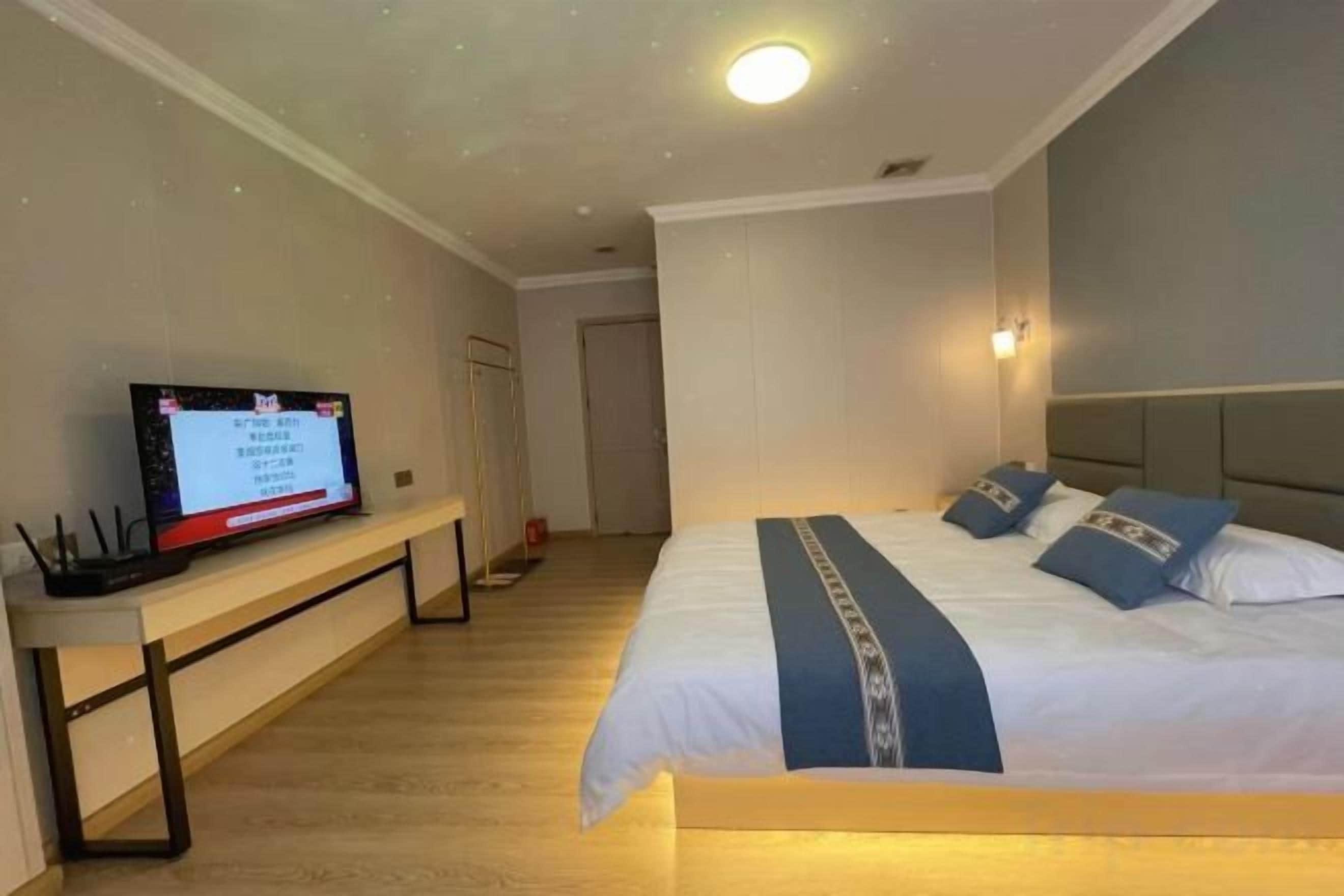 A hotel room with a bed, a desk with a computer, and a television.