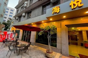 Un restaurant avec une terrasse, une plante en pot et une enseigne avec des caractères chinois.