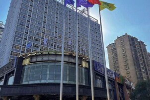 Un edificio de varios pisos con un llamativo frente de vidrio y una entrada circular.