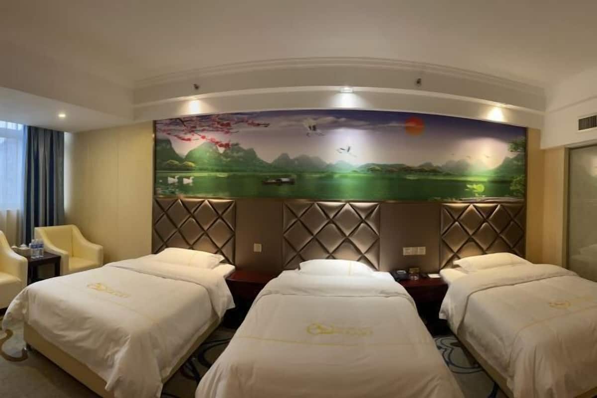 A hotel room with two beds, a large mural on the wall, and a view of the outdoors.