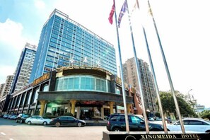 A hotel with a modern glass facade, a curved entrance, and a sign indicating it is the XINGMEIDA HOTEL. - Xing mei da Hotel (Changsha County)