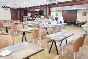 A hotel dining area with multiple tables and chairs, a reception desk, and a television screen. - Xing mei da Hotel (Changsha County)