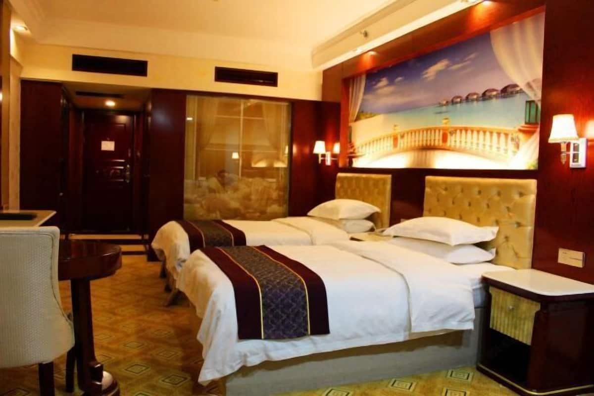 A hotel room with two beds, a small table, and a painting of a coastal scene.