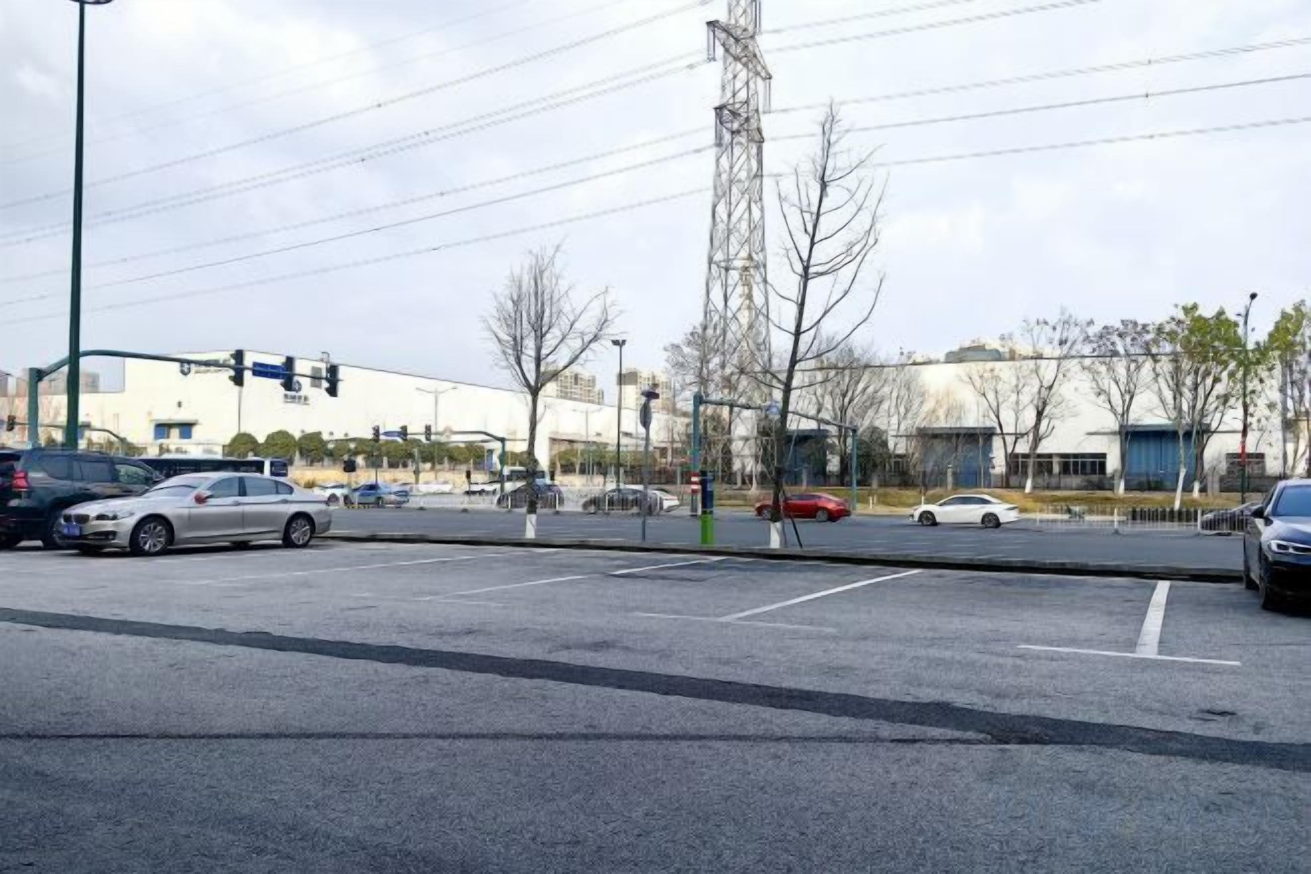 Un estacionamiento con varios autos, un semáforo y edificios al fondo.