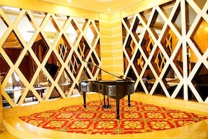 A grand piano in a room with a patterned carpet and a geometric white partition. - Xing mei da Hotel (Changsha County)