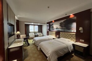 A hotel room with two beds, a desk, a chair, a painting on the wall, and a view of the outdoors. - Xing mei da Hotel (Changsha County)