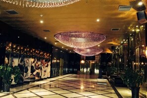 A hotel lobby with a tiled floor, large decorative light fixtures, and wall art. - Xing mei da Hotel (Changsha County)