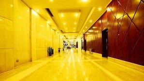 A long, well-lit hallway with a shiny floor, leading to a room with a patterned wall.