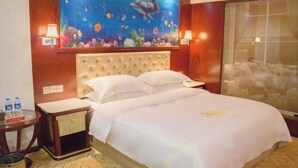 Una habitación de hotel con una cama grande, una mesita de noche, una pequeña mesa y un cuadro en la pared que representa una escena submarina.