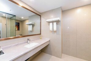 Un bagno moderno con uno specchio grande, un lavandino e un portascopevoli.