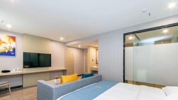 A modern hotel room with a bed, a sofa, a TV, and a desk. - Oukaihua Hotel (Guilin)