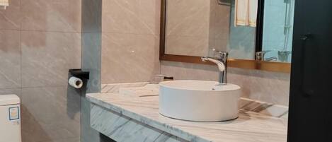 Un baño con encimera de mármol, un lavabo blanco, un espejo y un inodoro.