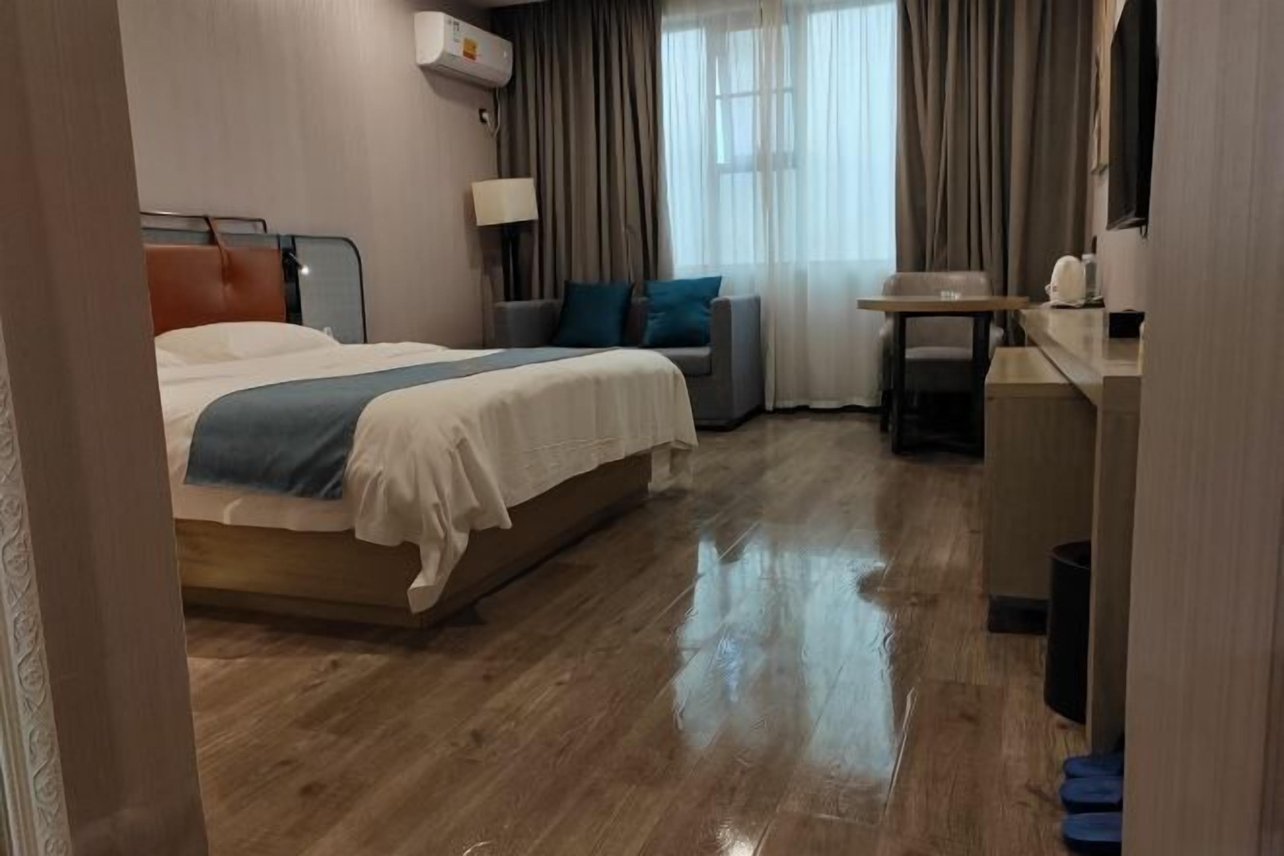 A hotel room with a bed, a sofa, a small table, and a desk.