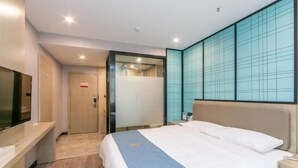 A hotel room with a bed, a TV, a desk, and a sliding door leading to a bathroom. - Oukaihua Hotel (Guilin)