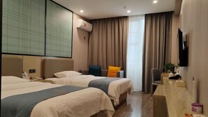 A hotel room with two beds, a desk, a chair, a TV, and a window with curtains. - Oukaihua Hotel (Guilin)