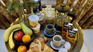 Een ontbijtplateau met fruit, gebak, koffie en toevoegingen op een tafel.