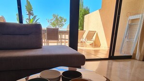 Uma sala de estar moderna com um sofá, uma mesa de centro com recipientes e vista para o exterior.
