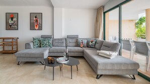 Uma sala de estar moderna com um sofá modular cinza, uma mesinha de centro e dois quadros de pássaros emoldurados na parede.