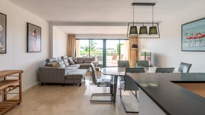 Uma sala de estar moderna com sofá, mesa de jantar, cadeiras e obras de arte nas paredes.
