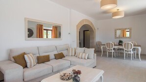 A living room with a sofa, coffee table, and dining area with chairs and a table.