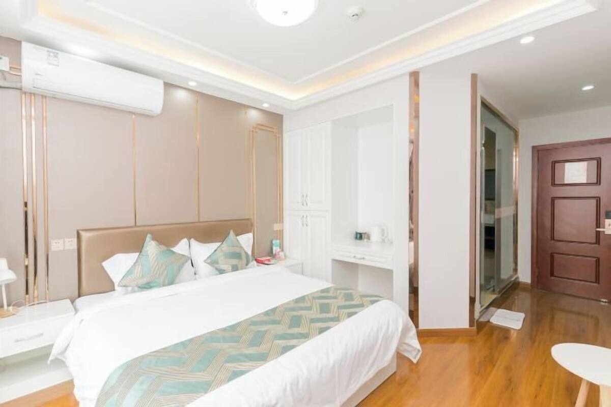 Une chambre d’hôtel moderne, dotée d’un grand lit, de tables de chevet, d’une armoire et d’une porte donnant accès à la salle de bain.