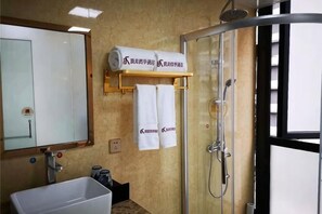 Une salle de bain équipée d’une baignoire, d’une douche à parois de verre, d’un porte-serviettes avec des serviettes et d’un miroir.
