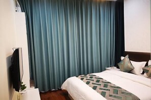 A hotel room with a bed, curtains, a TV, and a bedside table. - Kaibin Four Seasons Hotel (Renshou)