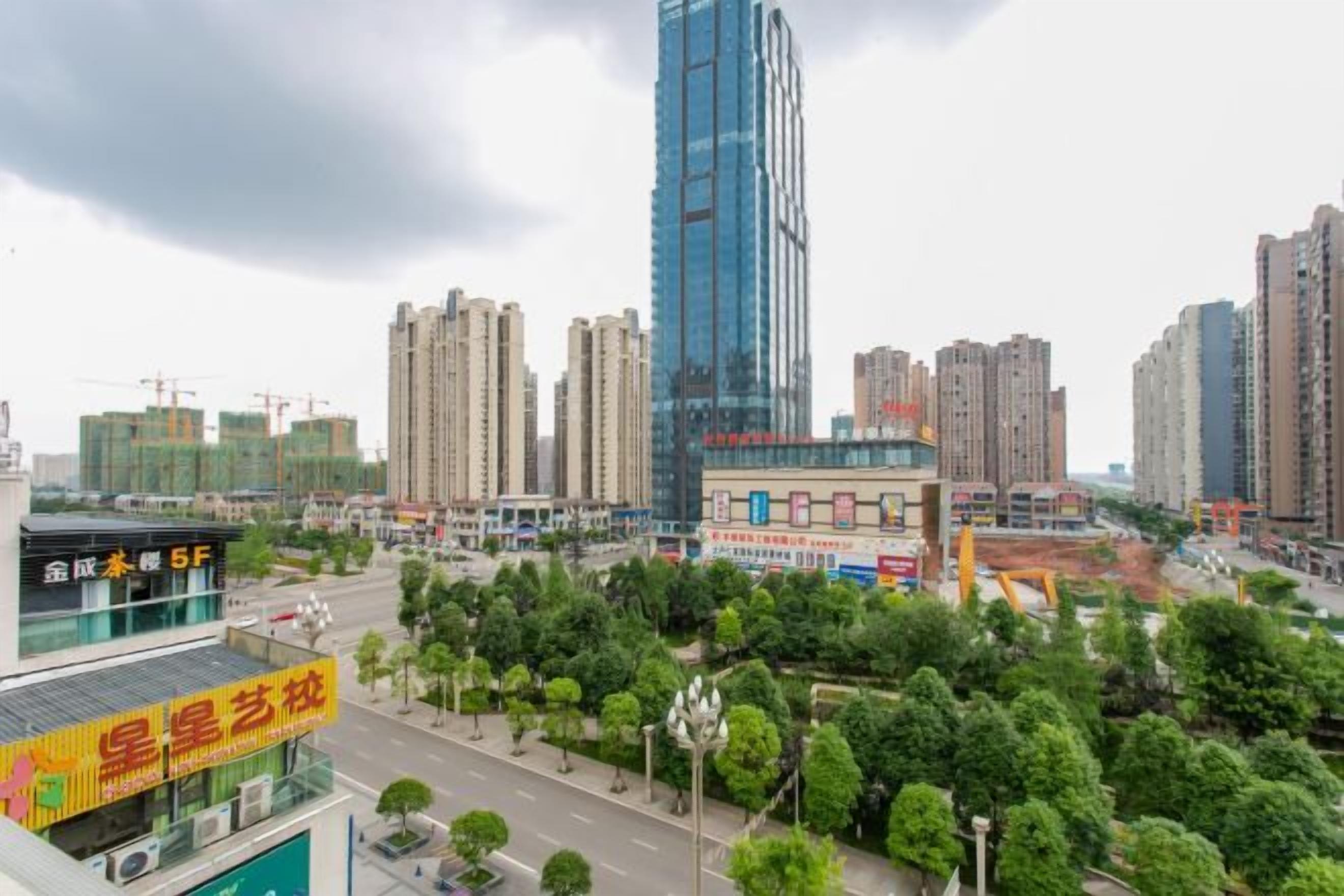 A cityscape with high-rise buildings, a bus stop, and a green park area.