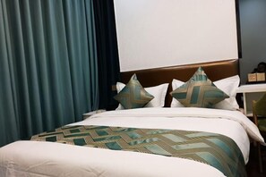 A bed with a patterned bedspread, pillows with geometric designs, and a dark curtain. - Kaibin Four Seasons Hotel (Renshou)