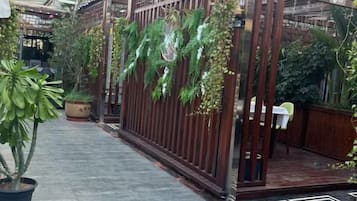 A courtyard with a wooden fence, potted plants, and a tiled floor.