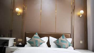 A hotel room with a bed, bedside tables, and wall-mounted lamps.