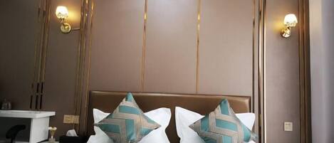 A hotel room with a bed, bedside tables, and wall-mounted lamps.