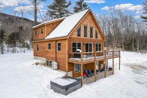 Una cabaña de madera con balcón, rodeada de nieve.