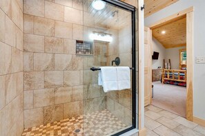 Ducha con puerta de cristal, suelo a cuadros y techo de madera.