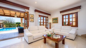 A living room with two sofas, a coffee table, and a pool view. - Villa Copinya Blanca in Santany with pool, garden, Wi-Fi, 5 minutes from the beach (santanyi)