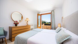 A bedroom with a bed, a dresser, a chair, a mirror, and a window with a view. - Villa Copinya Blanca in Santany with pool, garden, Wi-Fi, 5 minutes from the beach (santanyi)