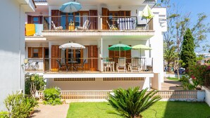 Un immeuble de deux étages doté de balcons, de mobilier d’extérieur et d’un jardin.