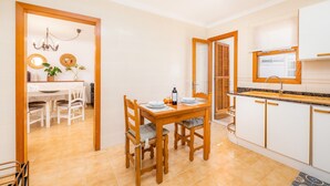Une cuisine moderne avec un coin repas, des meubles en bois et un lustre.